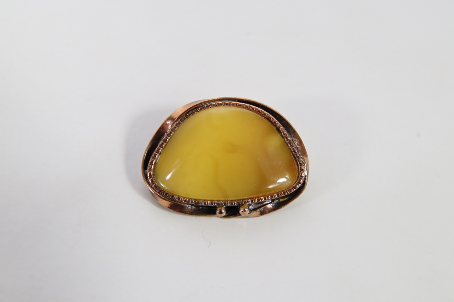 Brosje med gul stein i metallfatting