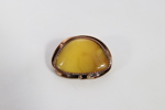 Brosje med gul stein i metallfatting