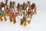 Samling håndskårne kamelfigurer i tre – 12 stk. lenket karavane