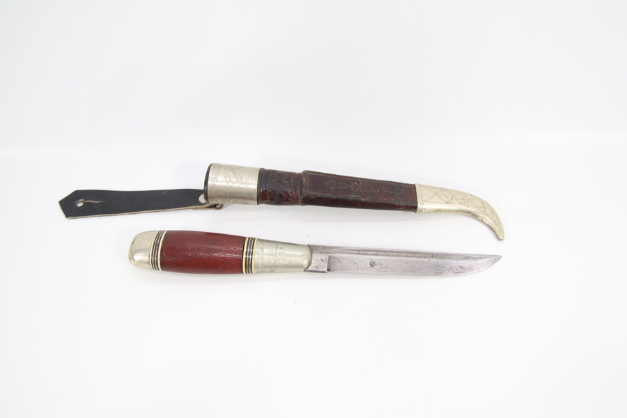 Dekorert kniv med lærslire og metallbeslag
