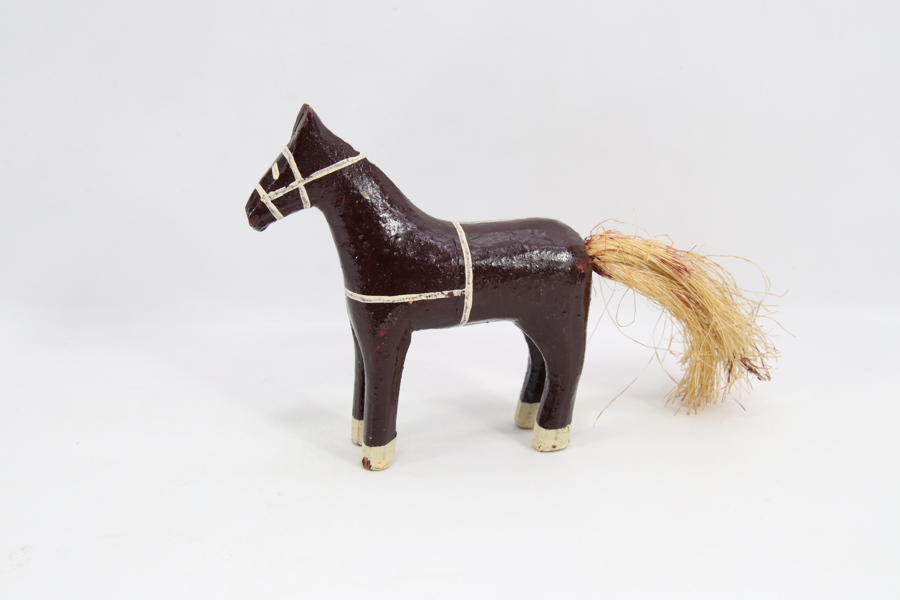 Håndskåret trehest med malt dekor og hale av naturfiber