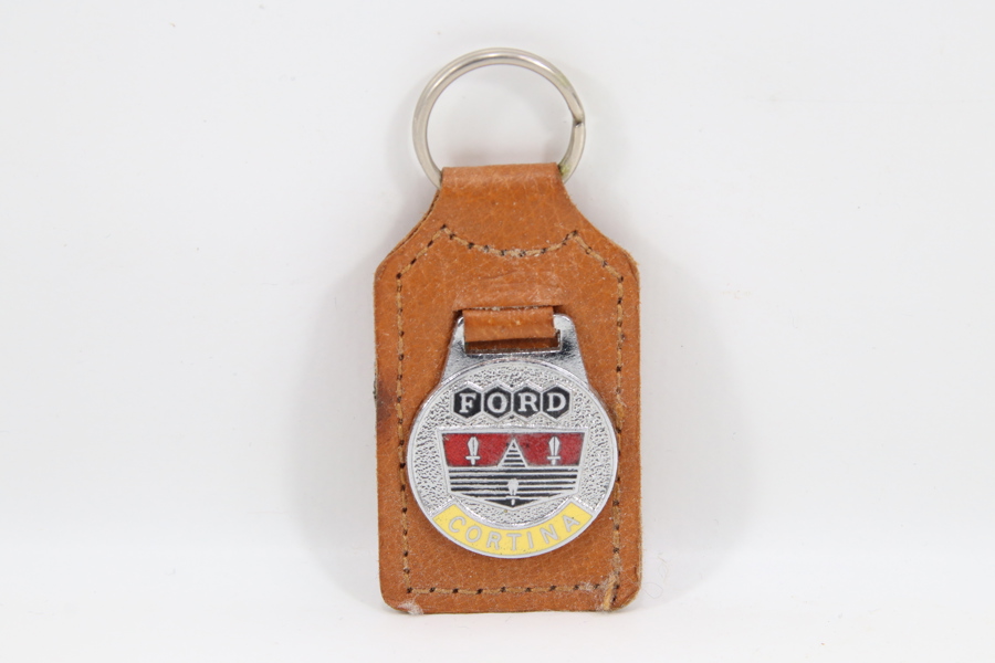 Eldre nøkkelring med skinnfeste og metallmerke – Ford Cortina
