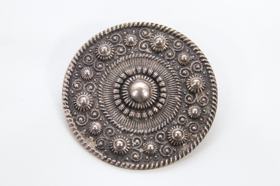 Rundt norsk draktsmykke med dekor
