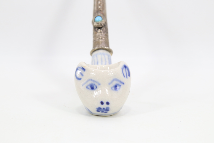 Eldre tobakkspipe med porselenshode og dekorert metallstamme
