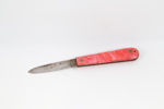 Liten eldre lommekniv med rød plastskala
